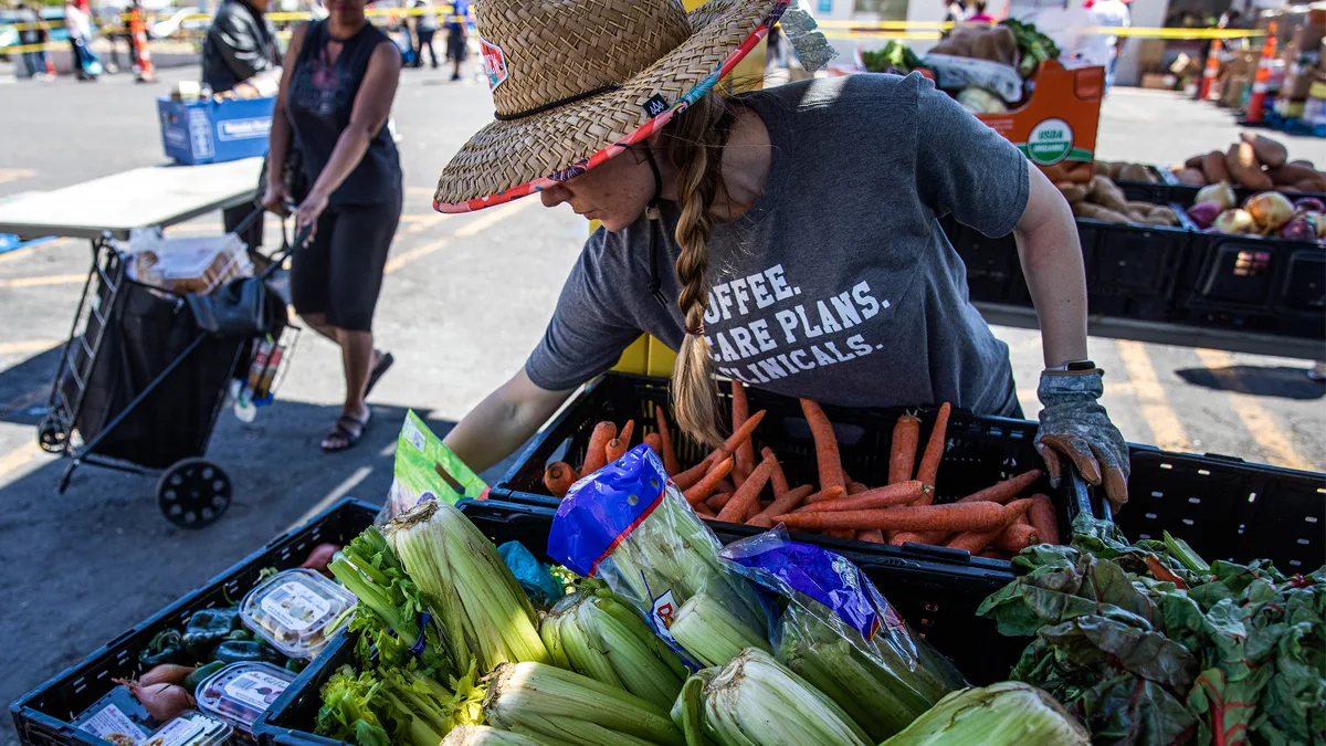 Photo of a volunteer overseeing a vegetable stand at an outdoor food pantry